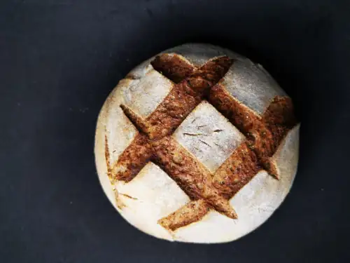 Hermosa fotografía de un pan de masa madre sin gluten, con un lindo greñado y corteza. Salud y sanación desde adentro hacia afuera.